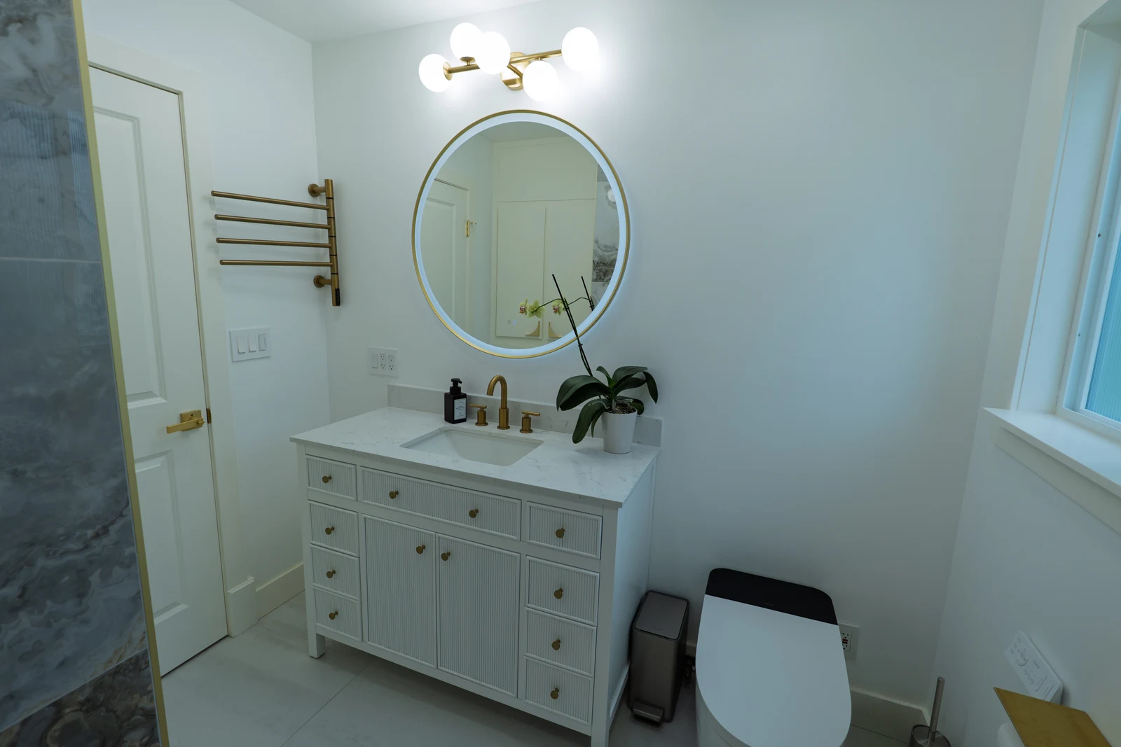 Bathroom vanity with brass fixtures, round mirror, and custom tile, Portland OR